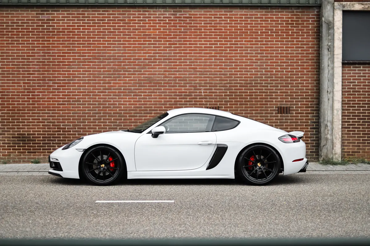 Porsche 718 Cayman in zijaanzicht tegen een bakstenen muur