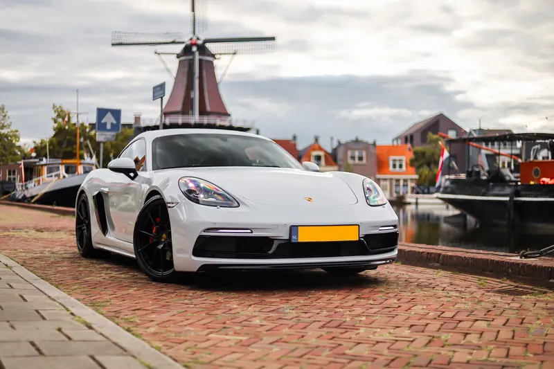 Porsche 718 Cayman aan het water met een molen op de achtergrond