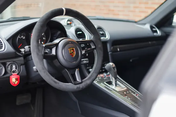 Vooraanzicht van de Porsche 718 Cayman tegen een bakstenen gevel